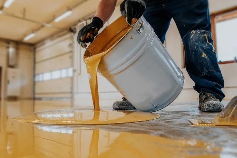 Pouring epoxy resin mixture onto a floor before spreading
