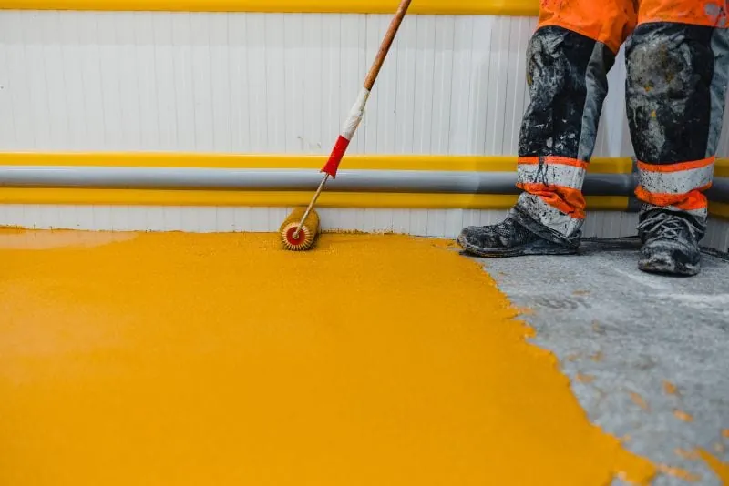 Installer applying yellow non-slip epoxy coating to a floor