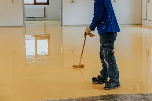 Installer rolling amber epoxy coating across a room floor