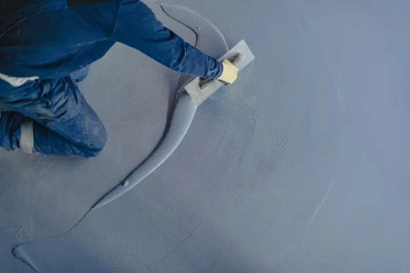 Tradesman trowelling a wet grey epoxy floor coating to a smooth, glossy finish