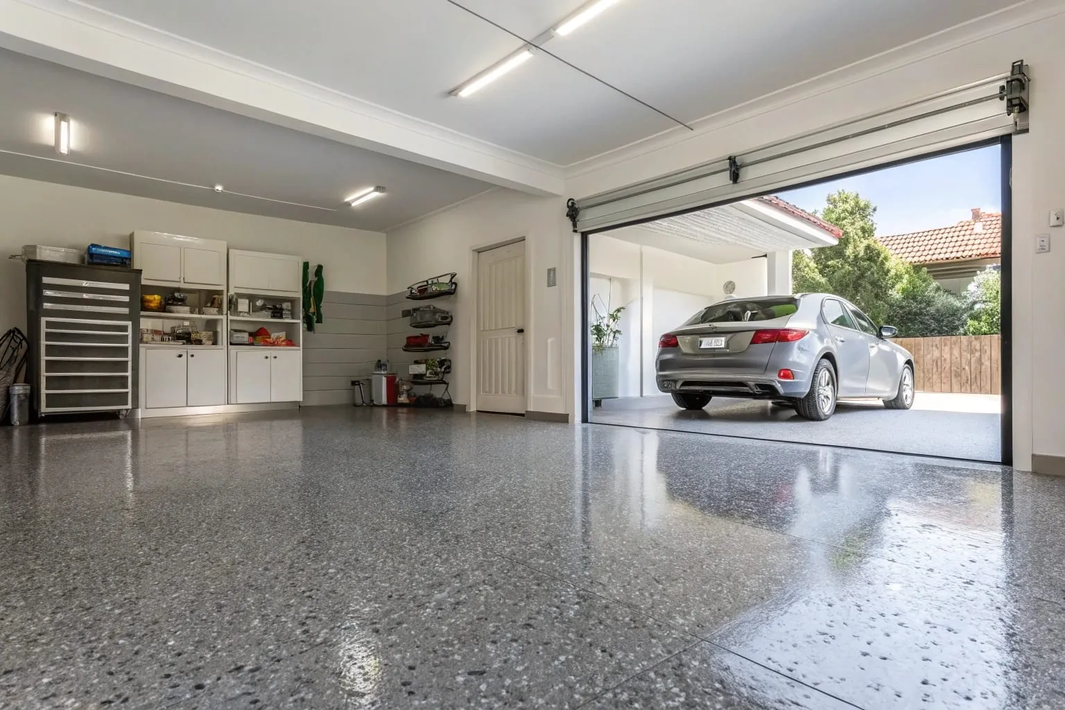 Modern grey epoxy garage floor coating with decorative flakes in a residential home